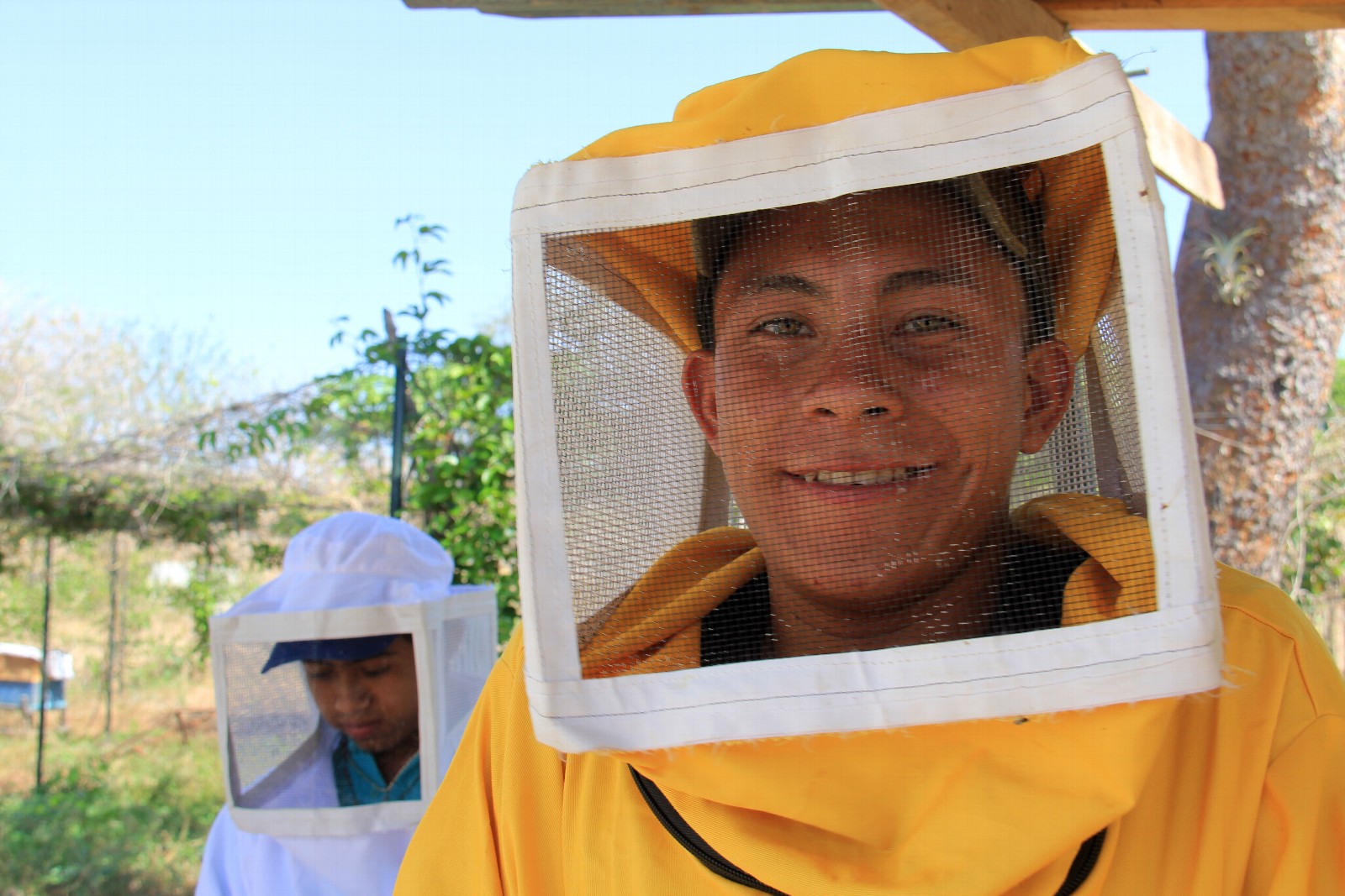 In the yellow suit, Ever Antonio Rios is a 17-year-old high school student from a low-income family in rural area of Somoto, Nicaragua. In his last year of high school, he graduated from CRS YouthBuild - an entrepreneurial and vocational training program - in beekeeping and entrepreneurship.   He created a business plan for his beekeeping business and now has 18 beehives.  He supports his family with the earnings from the honey, and teaches other YouthBuild youth about beekeeping.   