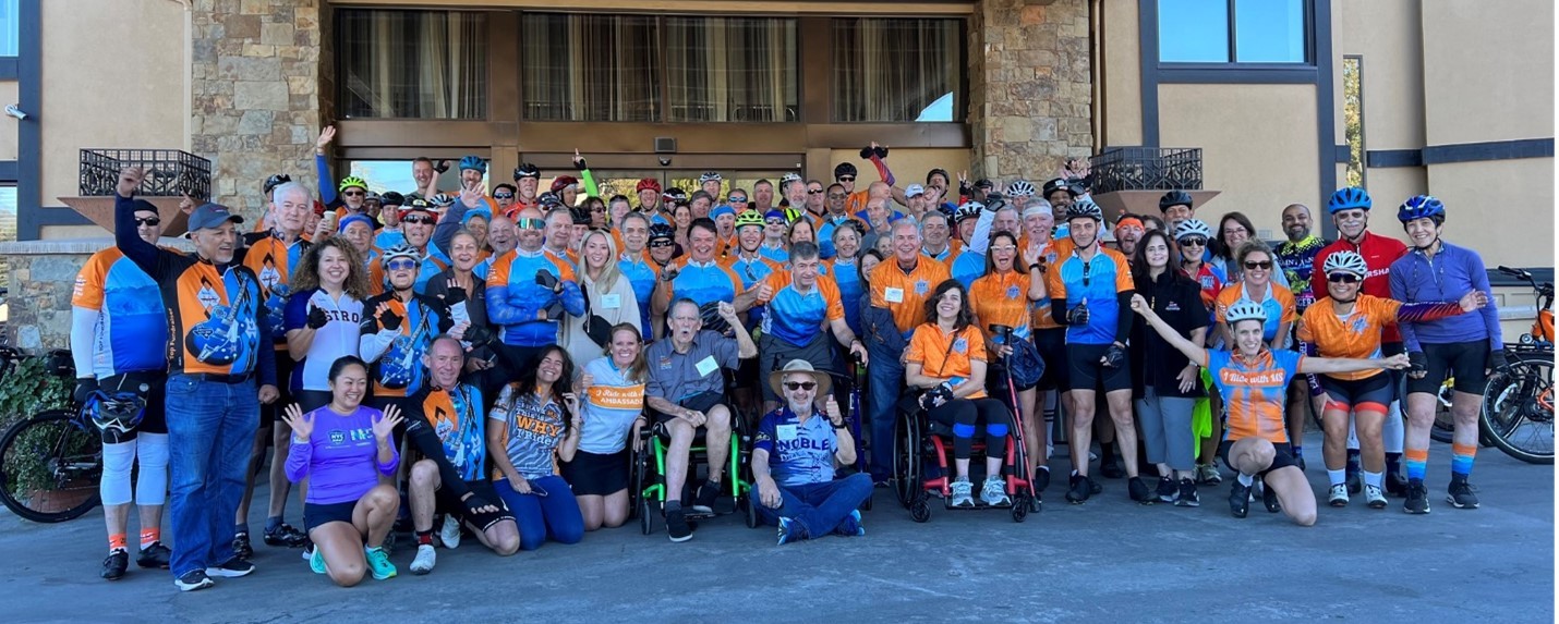 A group of large people getting there picture taken for the start of Bike MS: Texas MS 150 2024 in front of a hotel