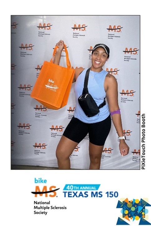 Woman holding orange bag poses in Bike MS photobooth