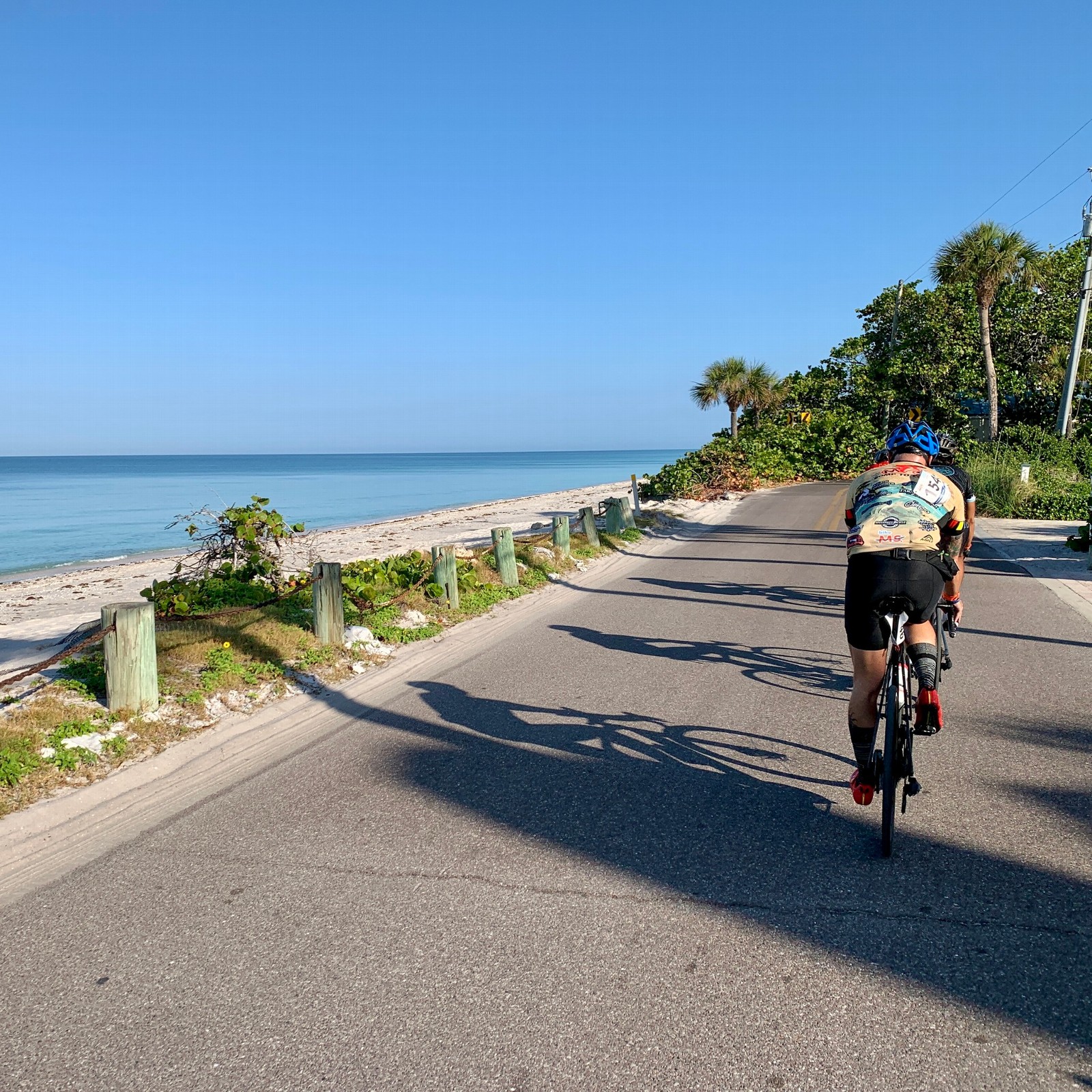 A cyclist rides on a bike path next to a view of the ocean