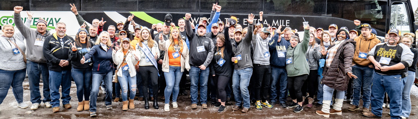 Large group of riders cheer in front of a bus