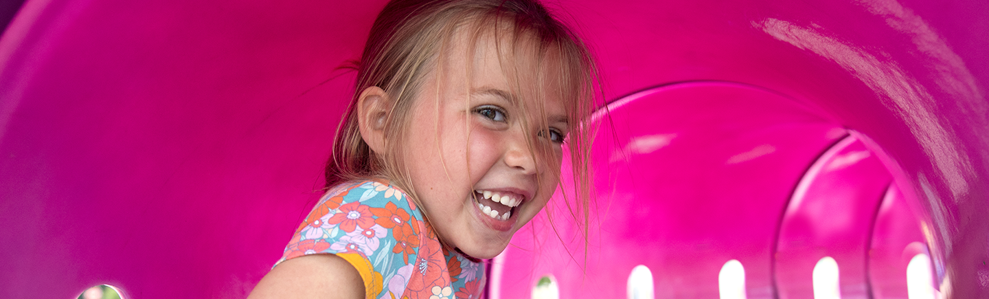 Miracle Child Bristol plays in a pink tunnel at a playground